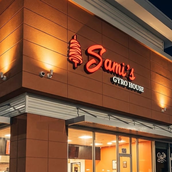 Exterior of Sami's Gyro House at night, with a glowing red sign and warm lighting on the building.