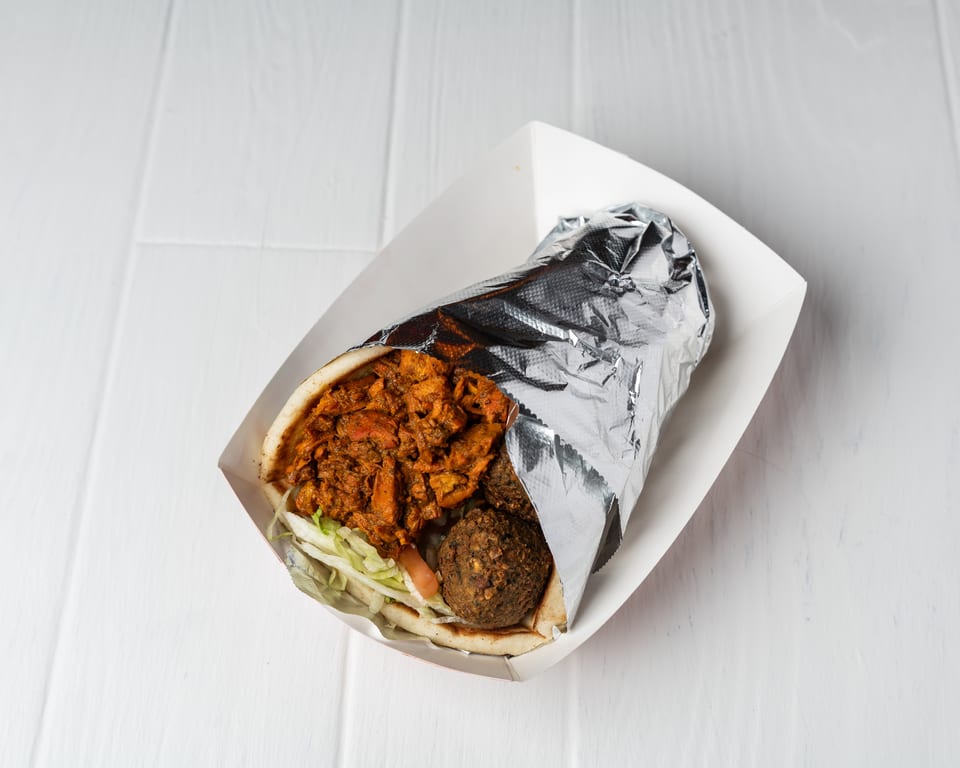 Chicken and falafel gyro in a white paper tray, partially wrapped in foil.