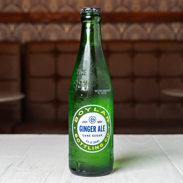 A green glass bottle of Boylan Ginger Ale with cane sugar sits on a white table.