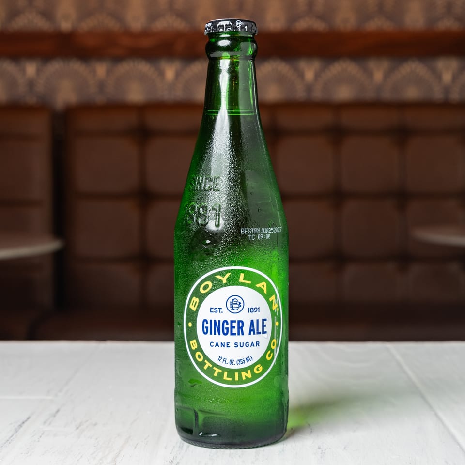 A green glass bottle of Boylan Ginger Ale with cane sugar sits on a white table.