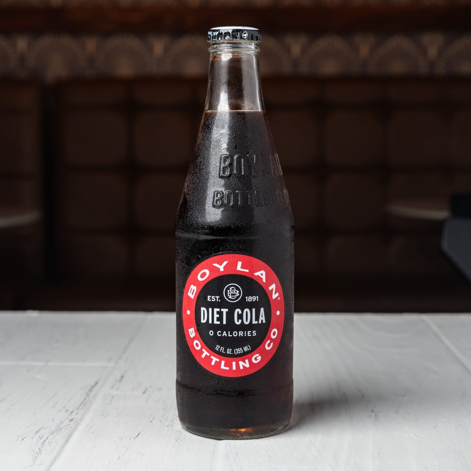 A cold, condensation-covered bottle of Boylan Diet Cola sits on a white table.