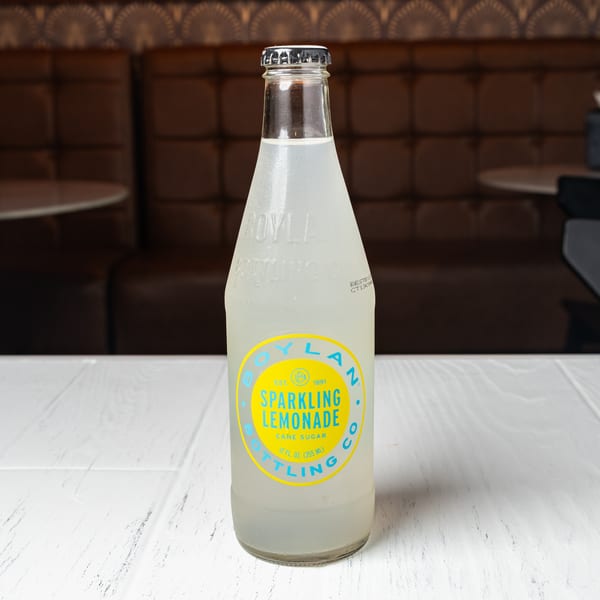 A bottle of Boylan Sparkling Lemonade sits on a white table in a restaurant booth.