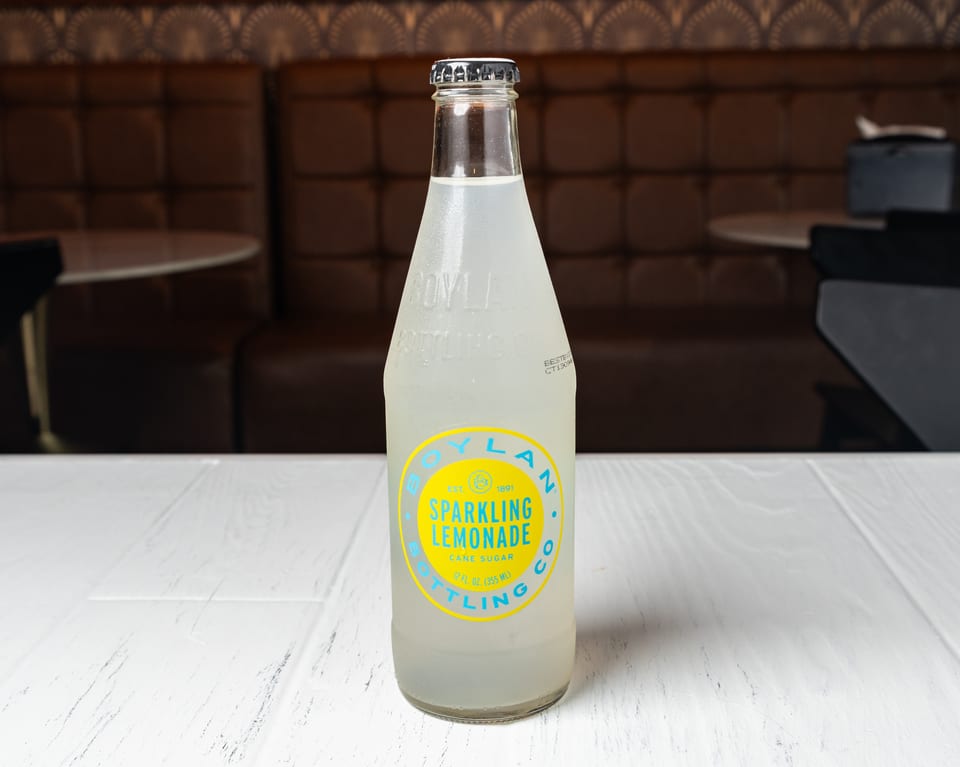 A bottle of Boylan Sparkling Lemonade sits on a white table in a restaurant booth.