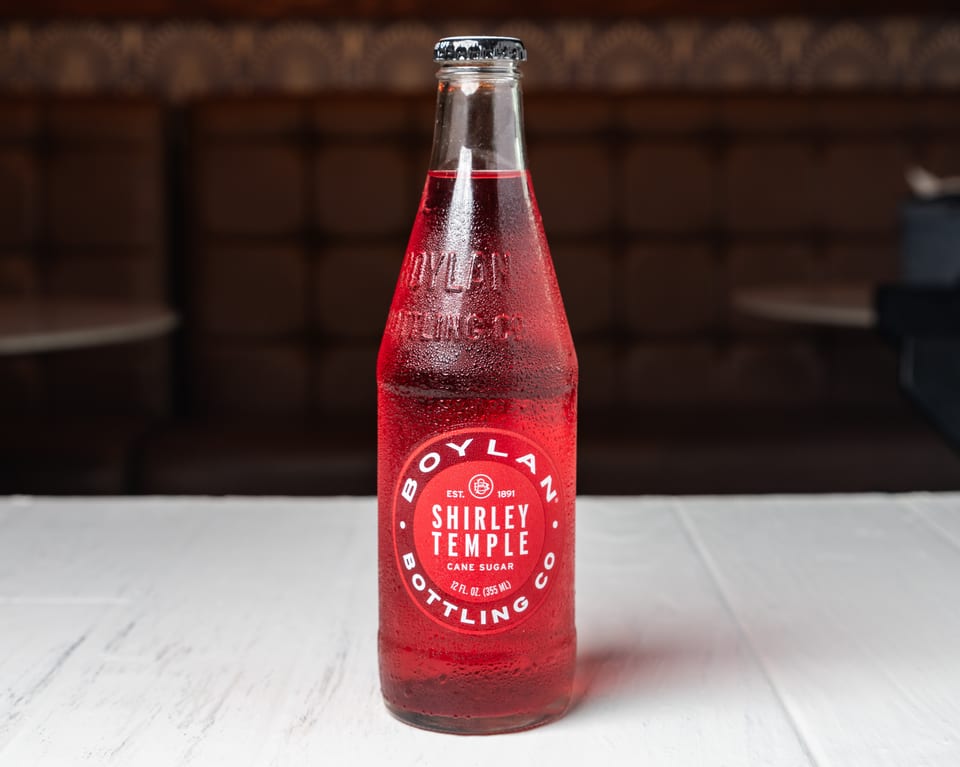 A cold bottle of Boylan Bottling Co. Shirley Temple soda on a white table.